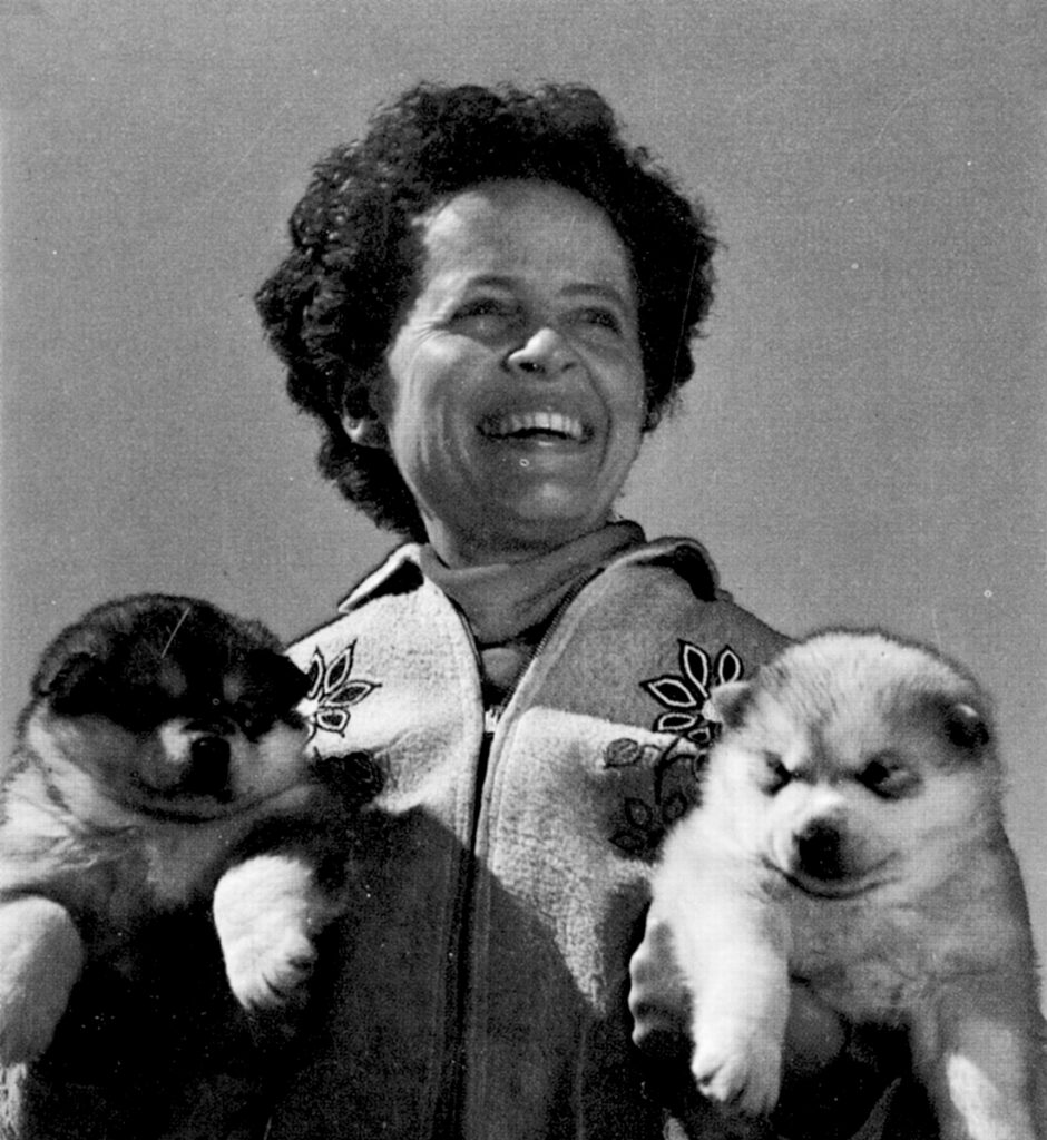 Head shot of Isabel Mace holding two huskie puppies